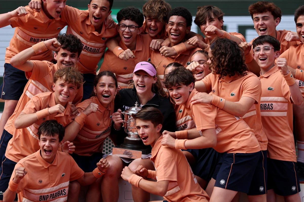 Russia's Mirra Andreeva celebrates with the trophy and ball kids after winning.
