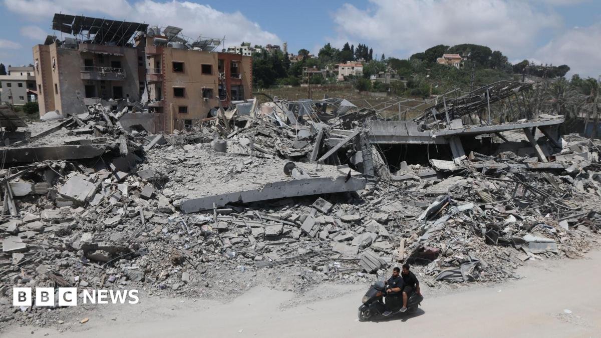 A man riding a motorcycle past destroyed buildings in the village of Mayfadoun, southern Lebanon (23 June 2026)