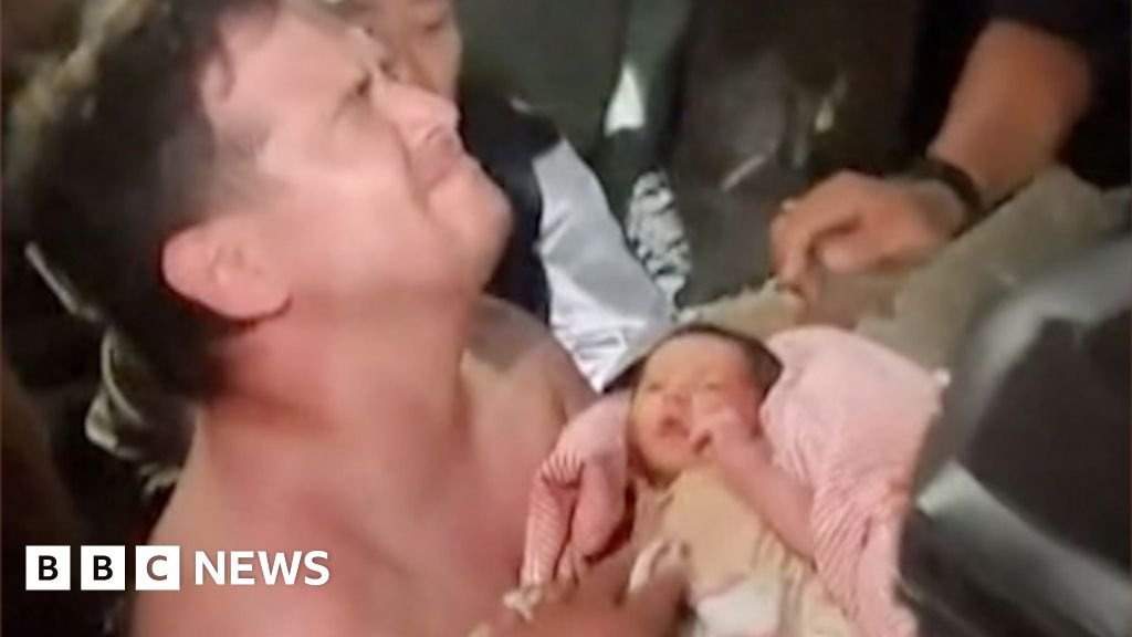 Emotional man holds baby wrapped in pink blanket
