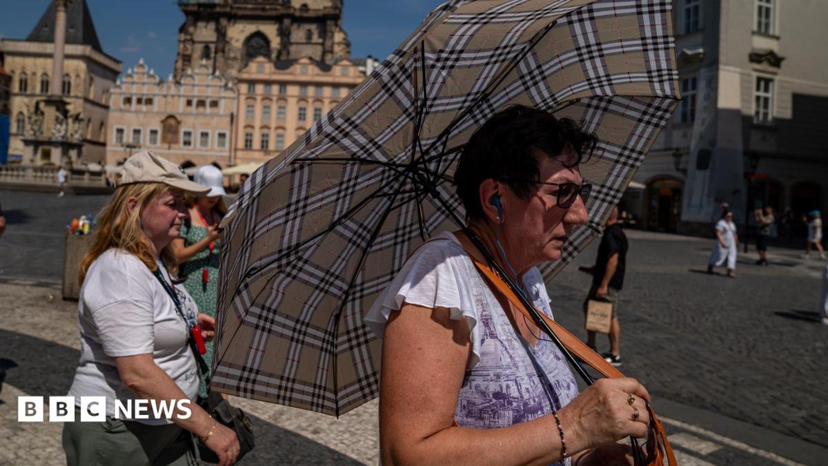 A woman with an umbrella shields herself from the sun in Prague's Old Town