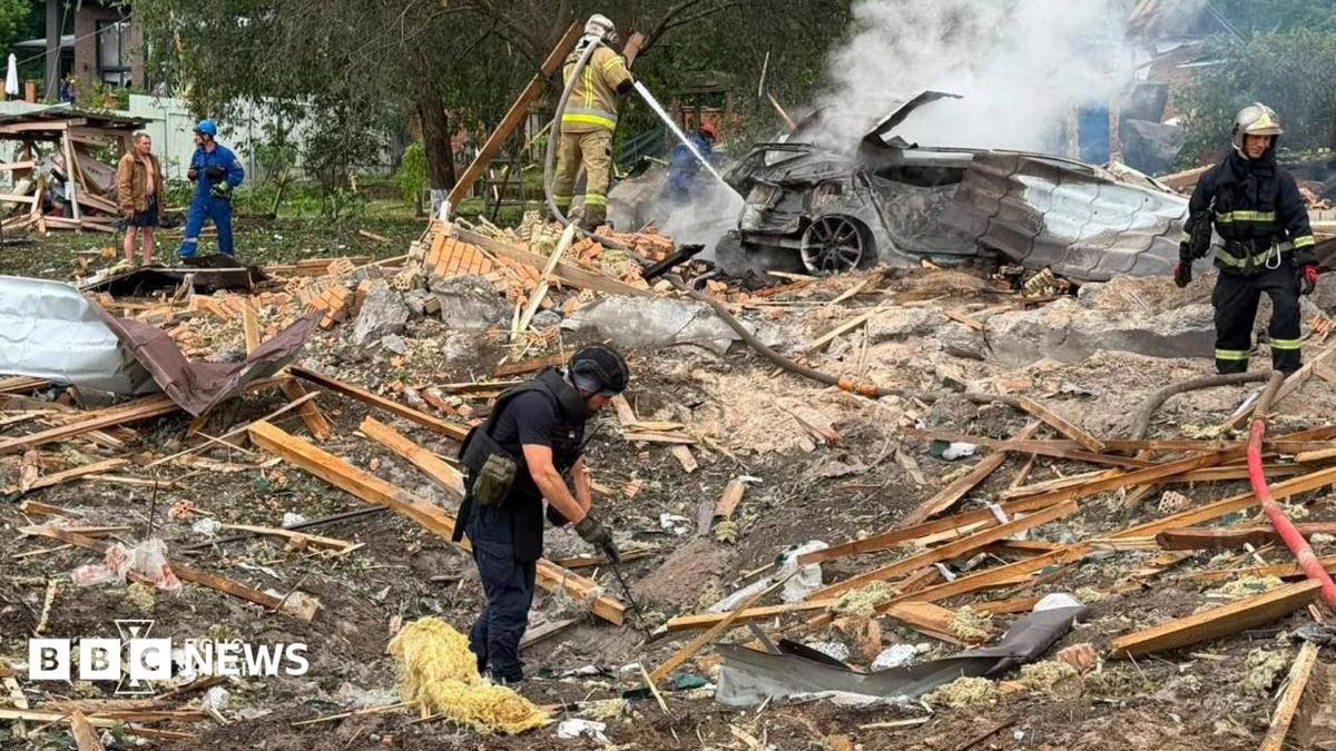 Emergency services clear through the rubble following a Russian missile strike just outside of Kyiv. Firefighters can be seen extinguishing a car fire in the background