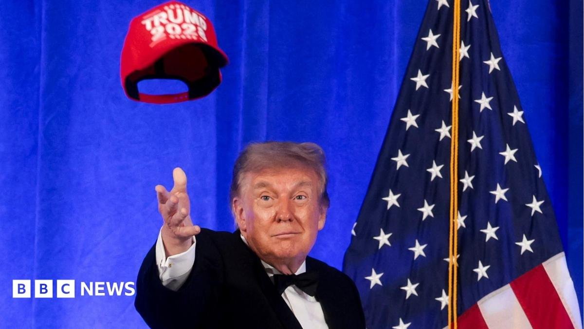 Trump in bow tie, before American flag, tosses red "Trump 2028" cap in air