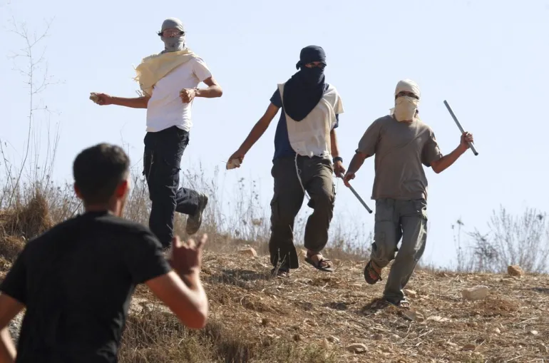 Masked Israeli settlers attack Palestinians in the West Bank village of Assira al-Kibliya. [File: Nasser Ishtayeh/AP]