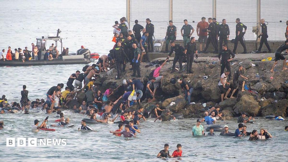 Dozens of migrants walking on a coastal path