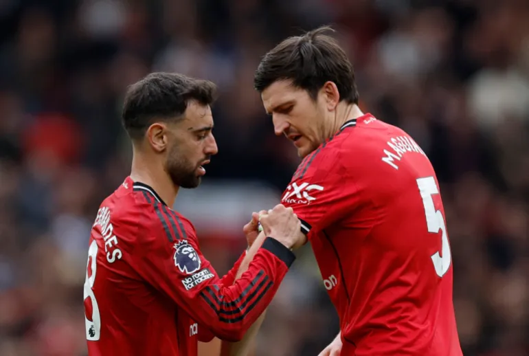 Manchester United’s Bruno Fernandes gives the captain’s armband to Harry Maguire during a game at Old Trafford