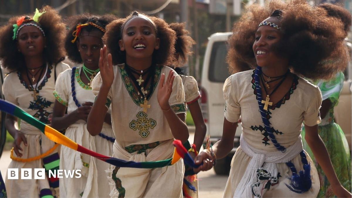 Orthodox Christian women clap as they walk down in traditional white outfits with silver cross necklaces in Mekelle in Ethiopia - archive shot