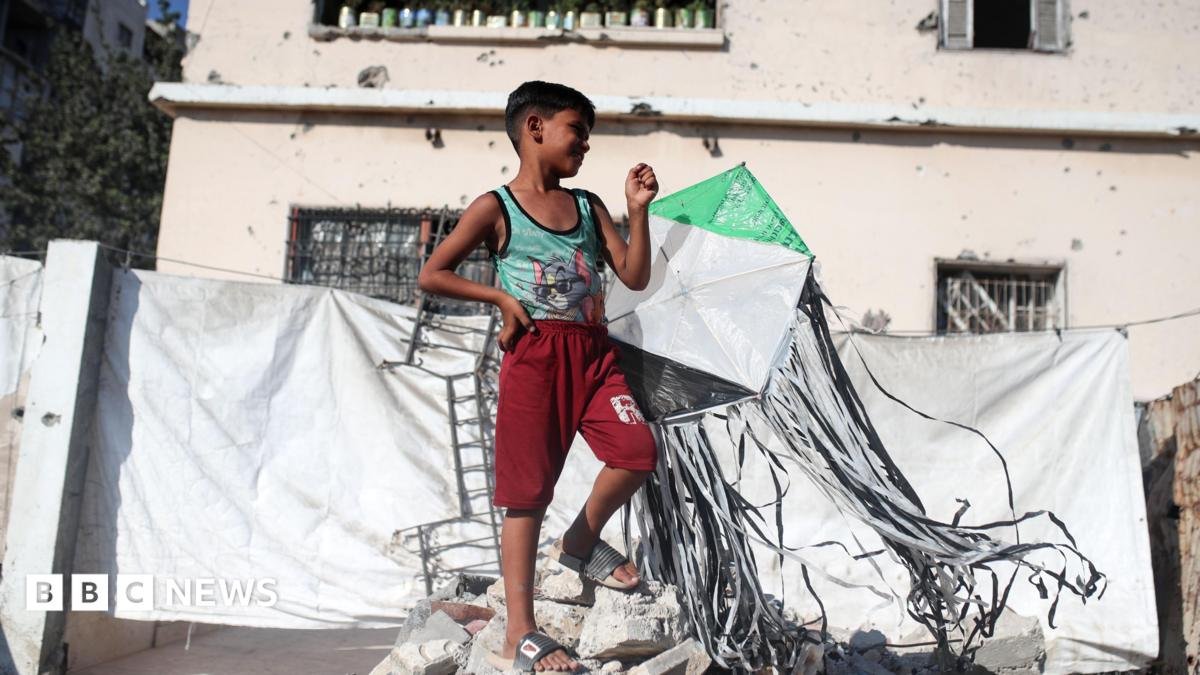 A Palestinian boy holds a kite at a displacement camp in Gaza City (23 August 2026)