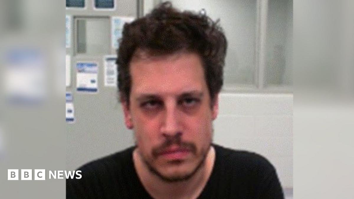 DHS released an mugshot of Yiannopoulos after his arrest. He wears a black shirt and has facial hair