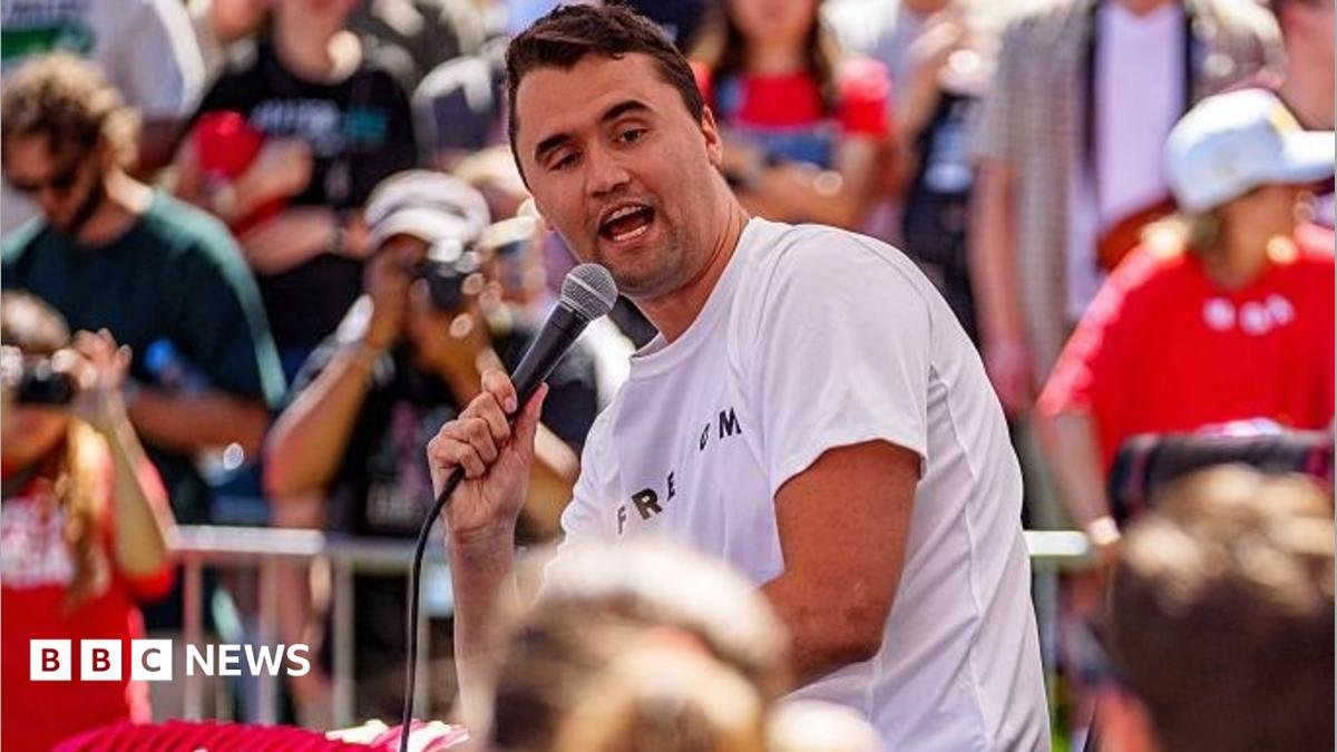 Charlie Kirk hold a microphone and speaks to a crowd of people at a university
