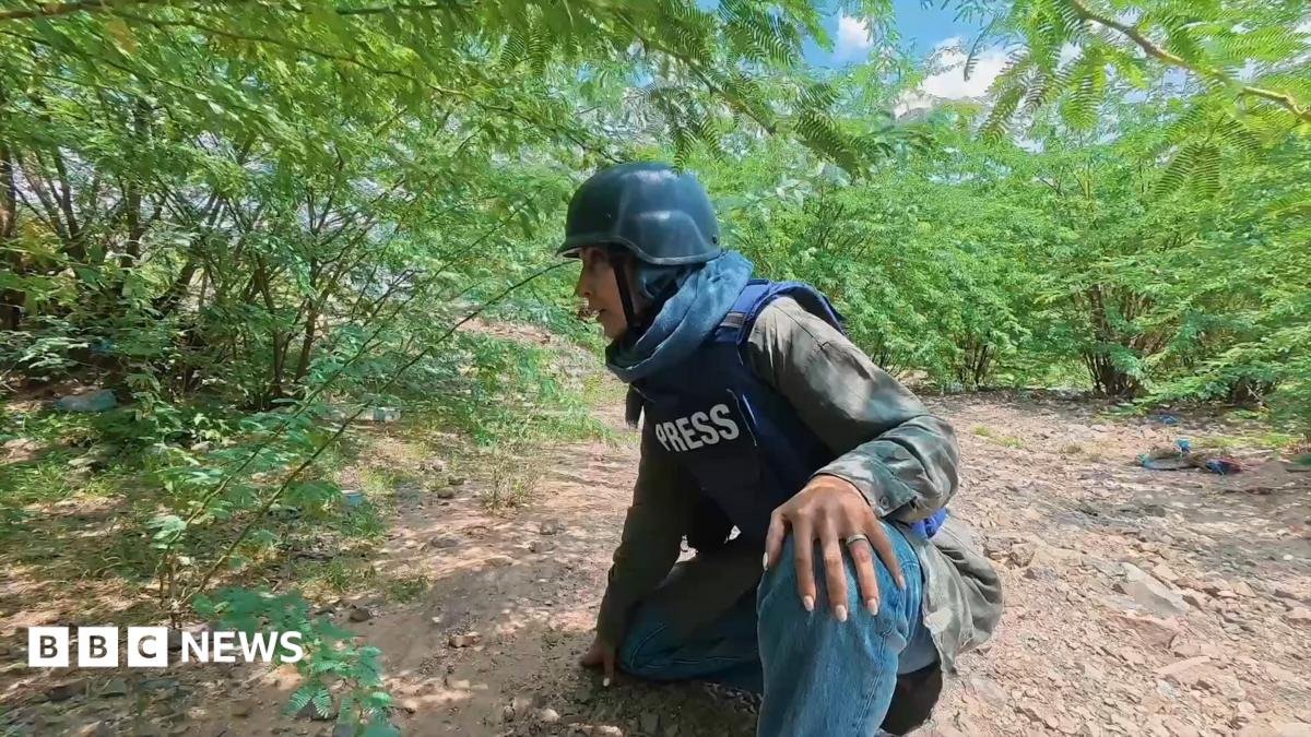 Nawal Al-Maghafi crouching down behind some bushes