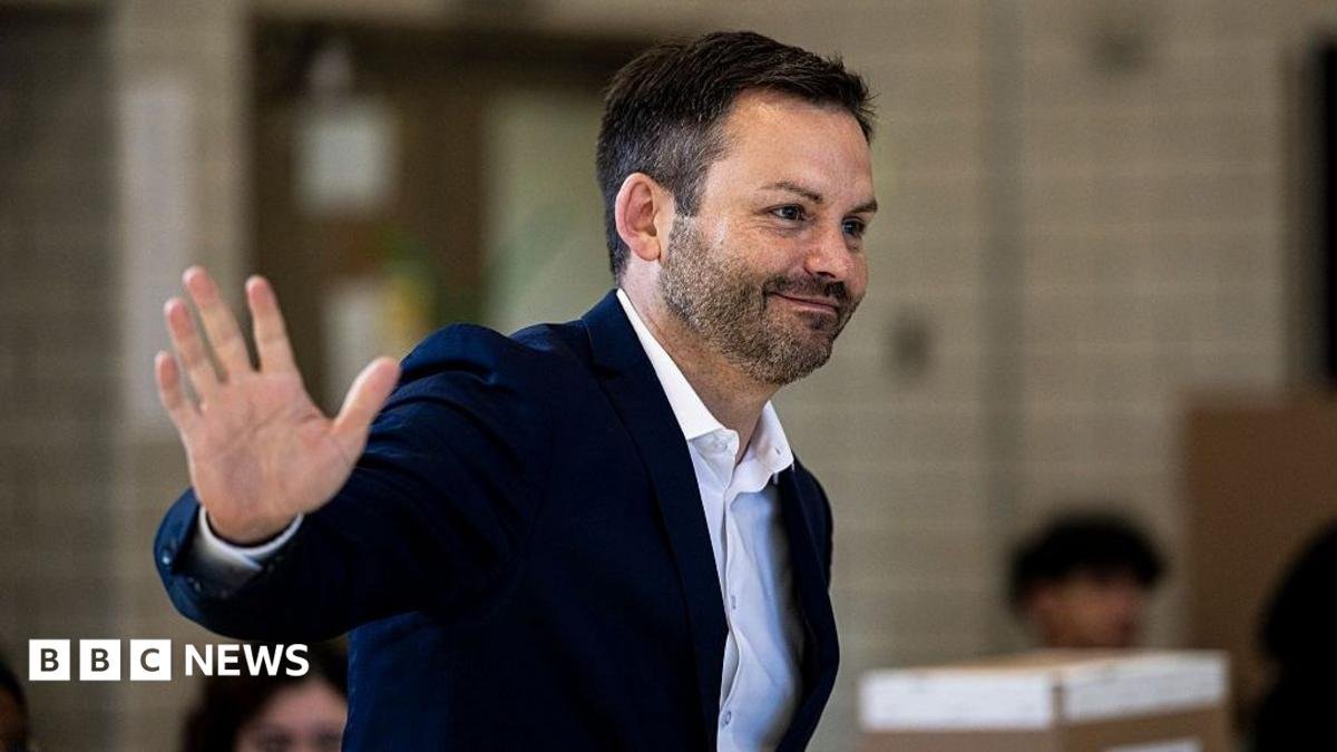 An image showing Paul St-Pierre Plamondon waving to supporters as he cast his ballot in the Quebec election on 5 October. He is wearing a navy blue suit jacket and a white button-up shirt. He has short black hair and a short beard.