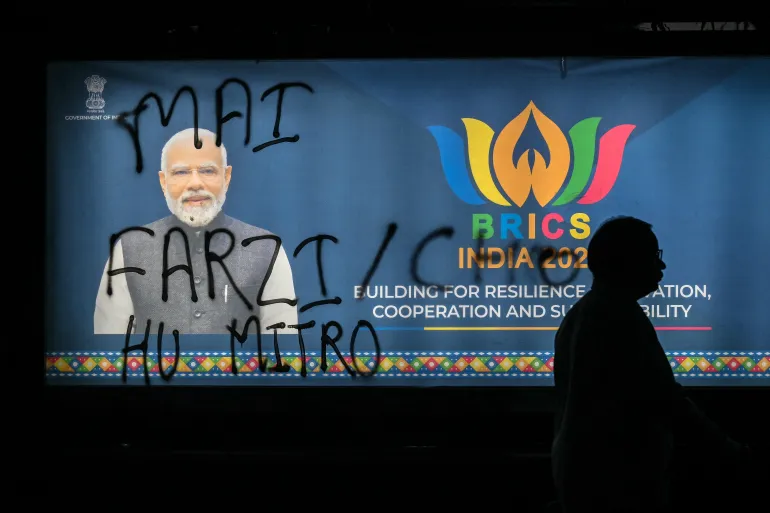 A man walks past a poster of India's Prime Minister Narendra Modi with graffiti on it during an ongoing protest by the opposition alliance INDIA bloc (Indian National Developmental Inclusive Alliance) in New Delhi on October 8, 2026, against the country's Chief Election Commissioner Gyanesh Kumar calling for his resignation over alleged irregularities in the Special Intensive Revision (SIR) of electoral rolls.